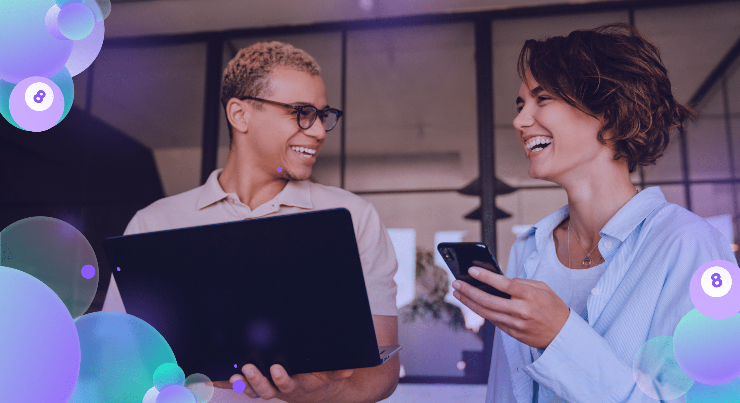 Two colleagues sharing a joyful moment with digital devices in a vibrant