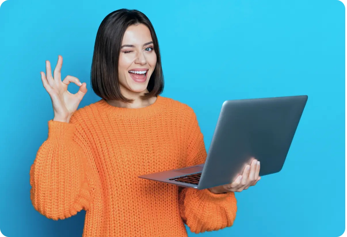 Cheerful female with laptop showing ‘perfect’ gesture, vibrant backdrop.