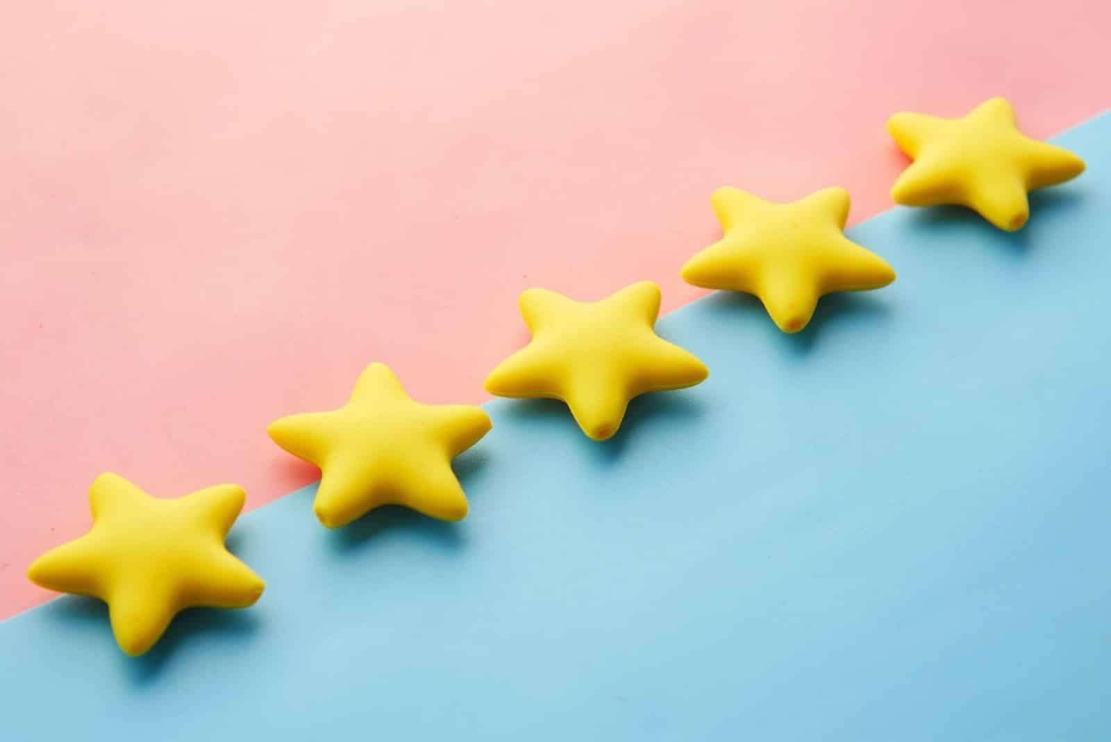 Get online reviews for your small business feature image. A diagonal line of yellow stars on a dual background with pink on the left and blue on the right for our article.